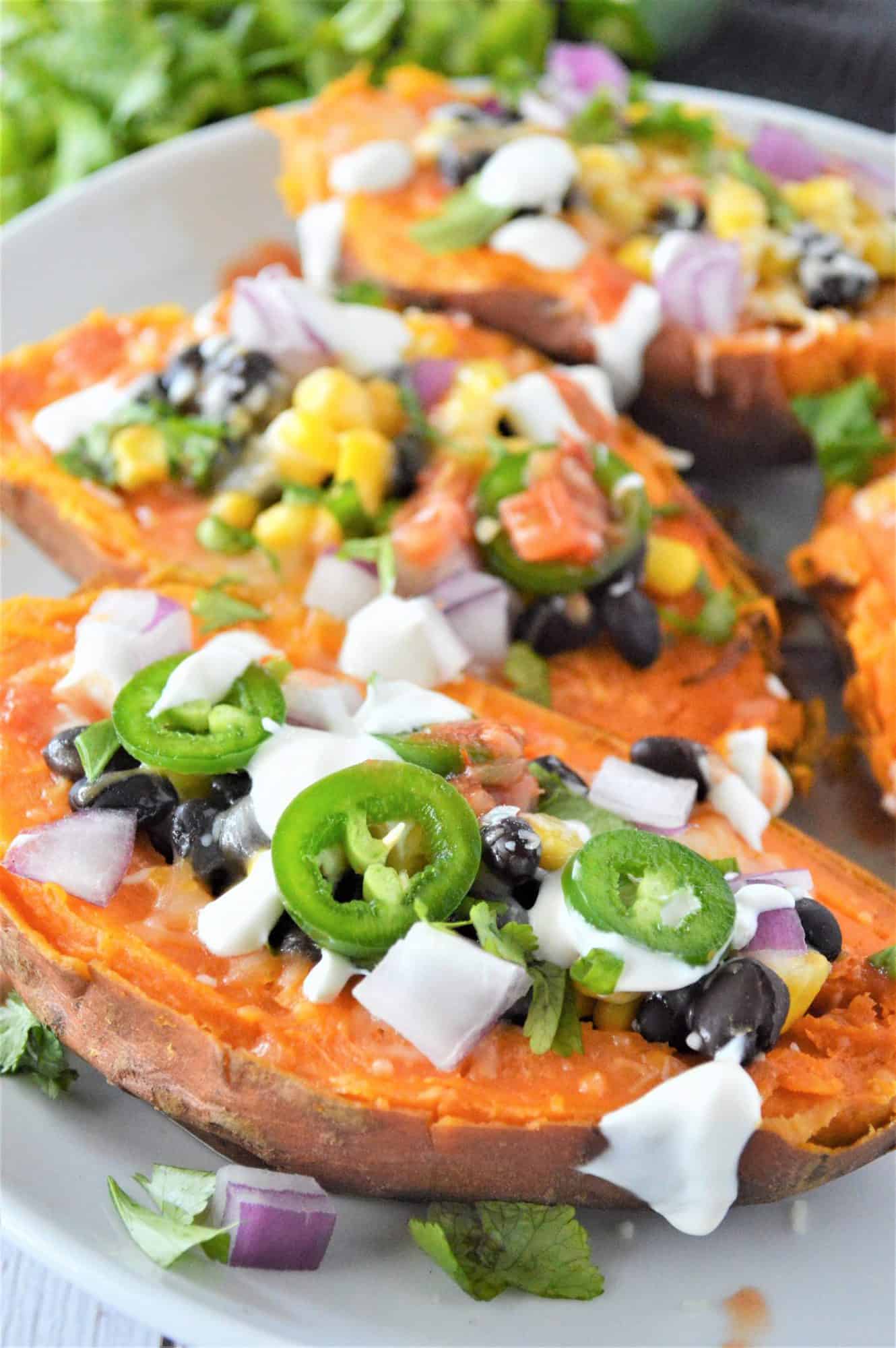3 sweet potatoes on a plate stuffed with toppings